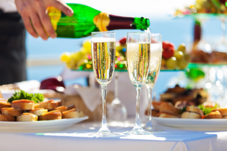 Champagne being poured with brunch food in background