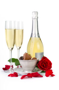 Romantic table decoration with rose petals, champagne and chocolates on a white background