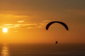 paraglider with sunset in background over ocean